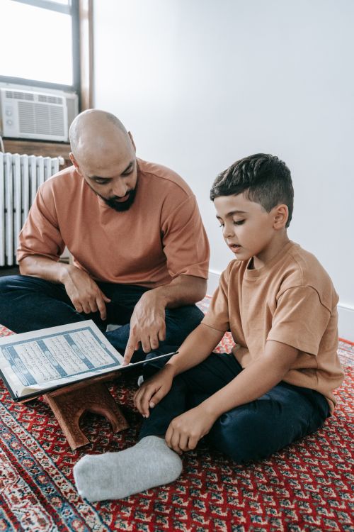 Free Father and son sitting together, focusing on religious teaching at home. Engaged and peaceful scene. Stock Photo