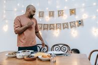 A family celebrating Eid indoors with festive meal and decorations, creating a joyful and warm atmosphere.