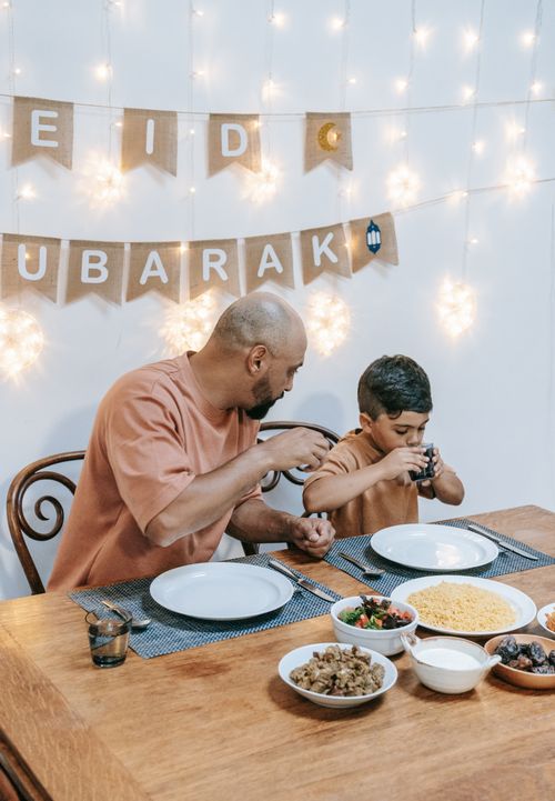 Free Father and son enjoying a festive meal together at home during Eid celebrations. Stock Photo