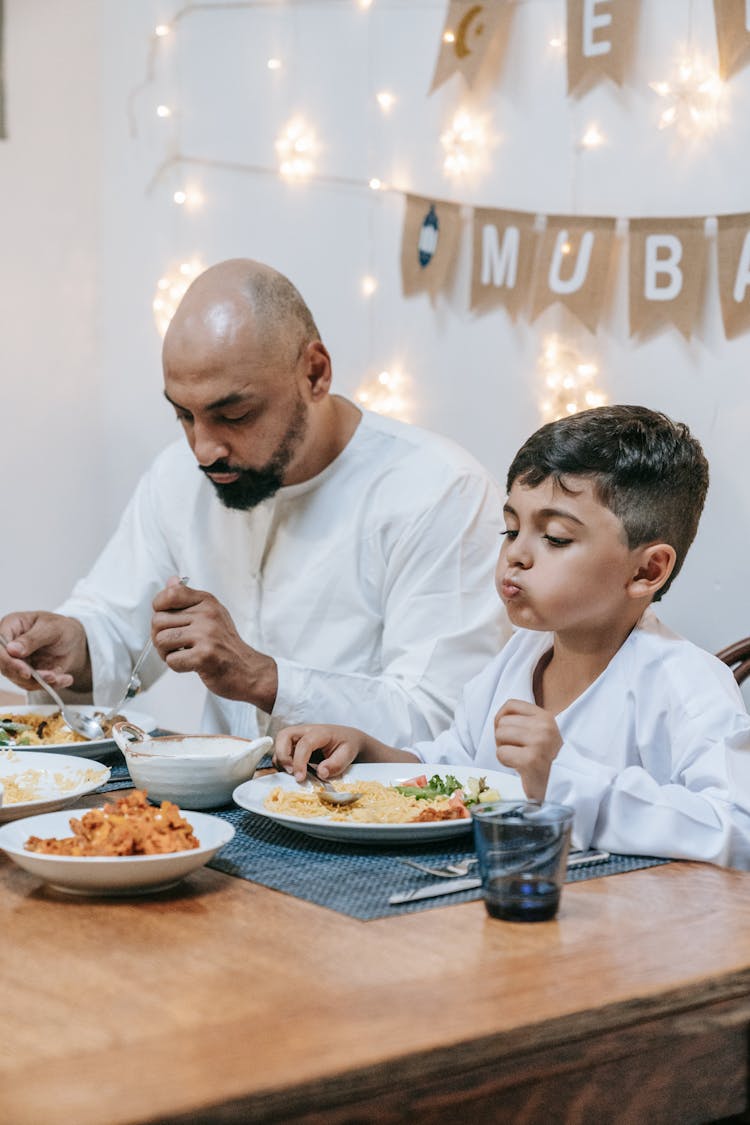 Father And Son Eating On The Table