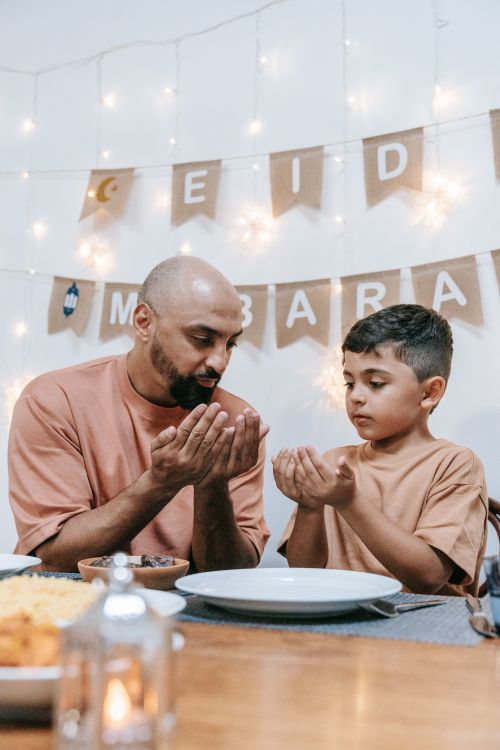 Free A touching moment of father and son praying together at an Eid celebration dinner. Stock Photo