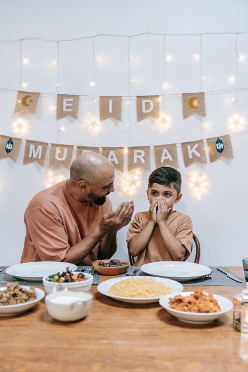 Free Father and son enjoying Eid celebrations together around the dinner table. Stock Photo