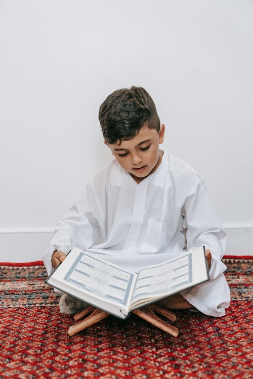 Boy Sitting on the Floor and Reading a Book 