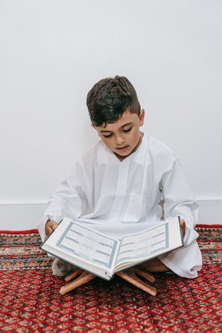 Boy Sitting On The Floor And Reading A Book 