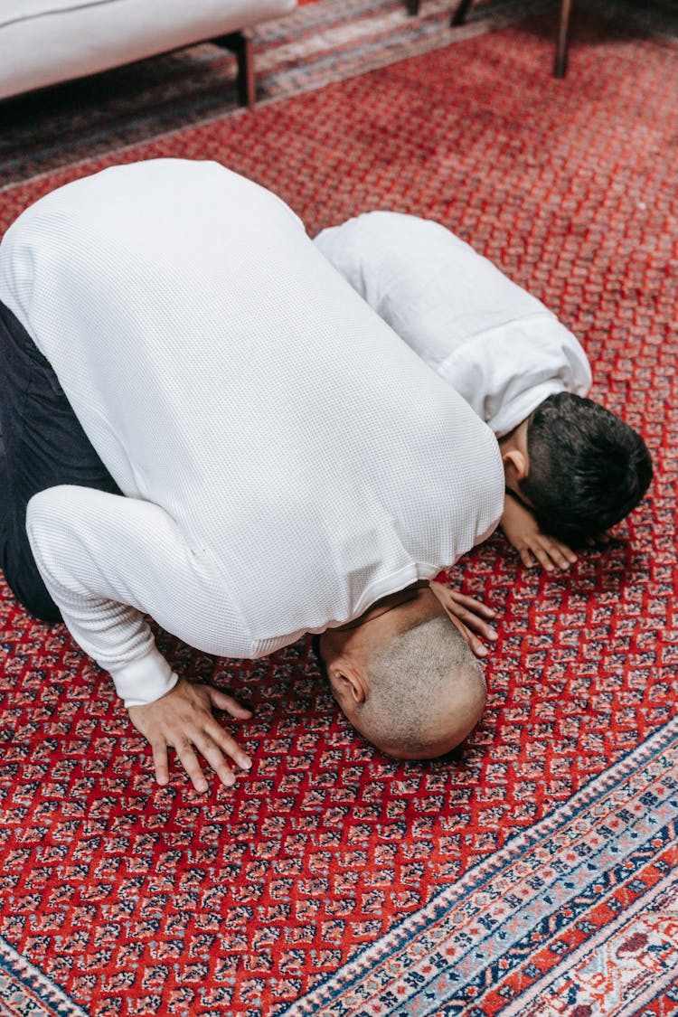 A Man And A Boy Bowing Down On A Red Rug