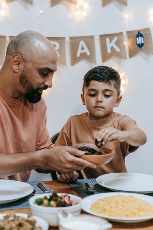 Free A father and son enjoying a traditional meal together during Ramadan, symbolizing family bonding. Stock Photo