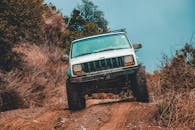 一辆坚固的吉普车正穿越茂密森林中一条泥泞难行的越野小径