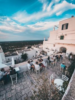 Captivating rooftop dining scene in Ostuni under a vibrant summer sky.