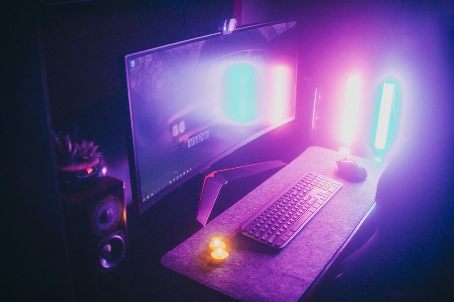 Desk setup washed in magenta and teal light bars at night — photo by Matheus Bertelli on Pexels