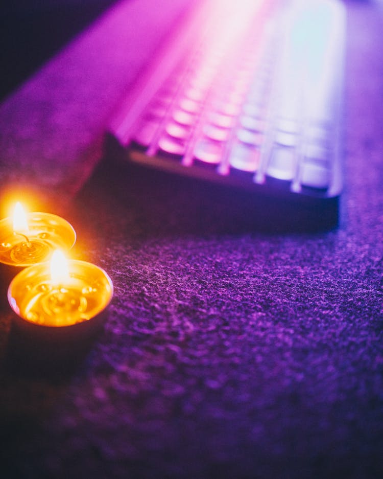 A Pair Of Lighted Candles Melting On Round Containers