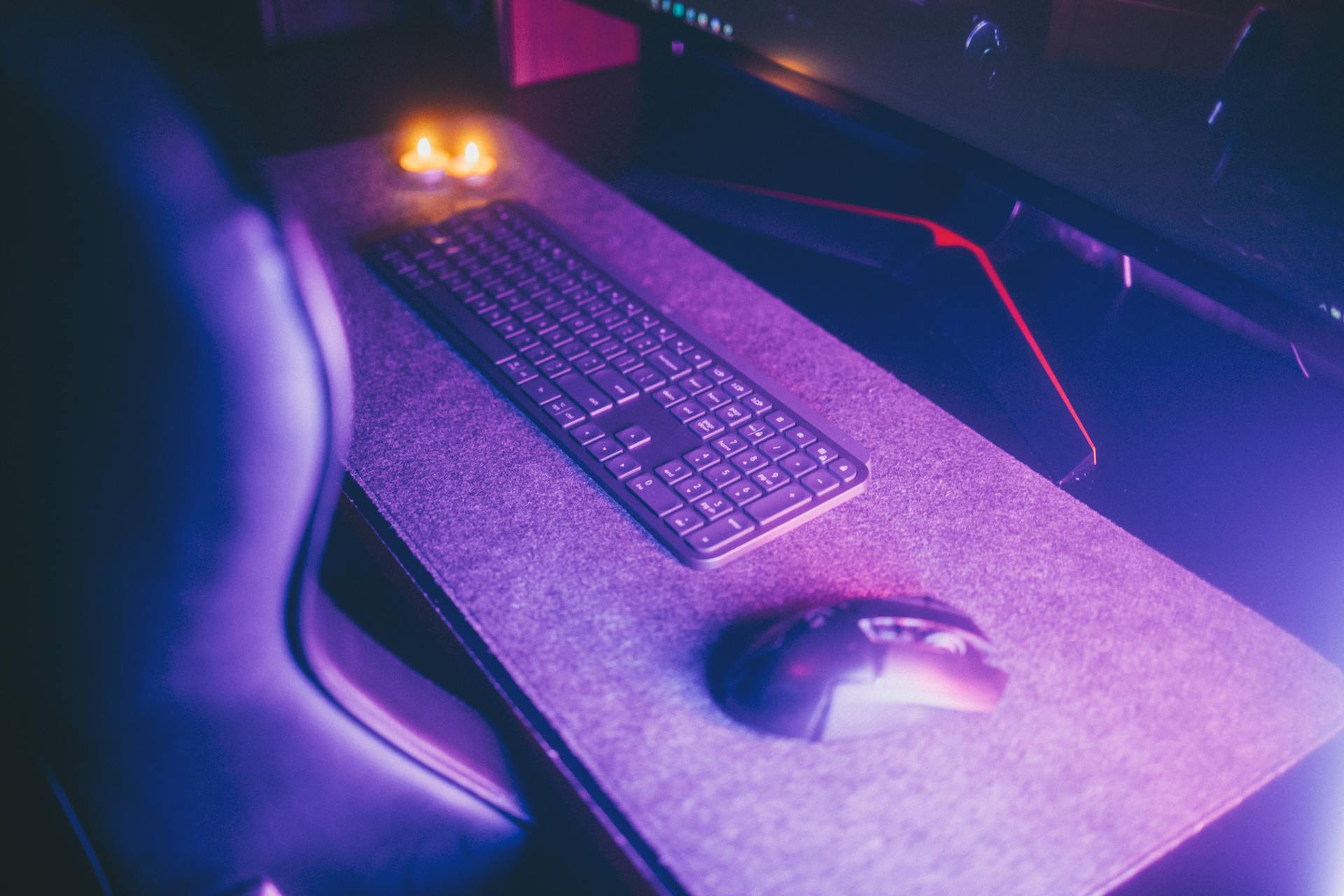 Stylish computer desk setup featuring a keyboard and mouse under ambient lighting.