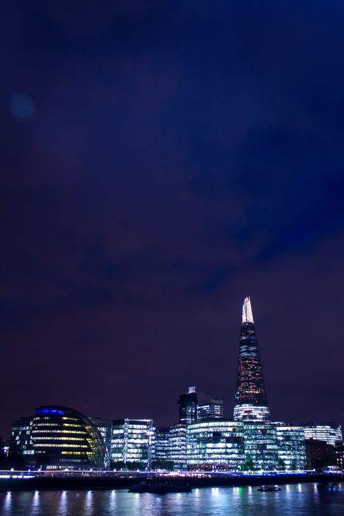 Free Stunning nighttime view of London's skyline, featuring The Shard and city lights reflecting off the Thames river. Stock Photo