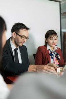 Two professionals engaged in a business meeting, seated at a conference table.