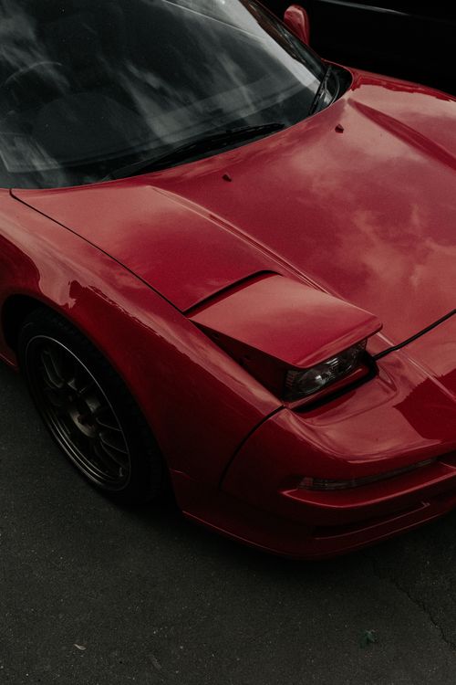 Free Close-up of a red sports car parked on a pavement, showcasing sleek design. Stock Photo