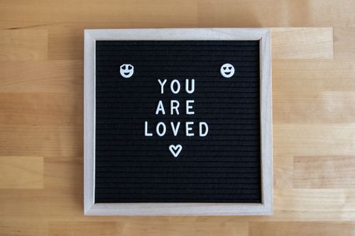 Free Letter board with 'You Are Loved' message on a wooden surface, conveying warmth and positivity. Stock Photo