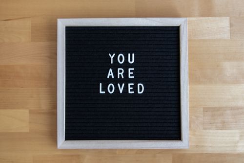 Free A minimalist text board with 'You Are Loved' message on a wooden table. Stock Photo
