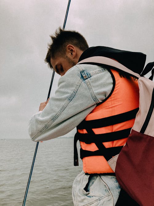 A Man in Denim Jacket Wearing an Orange Life Vest