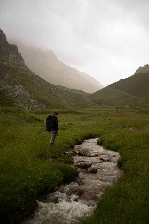 Man in Black Jacket Walking on a Valley