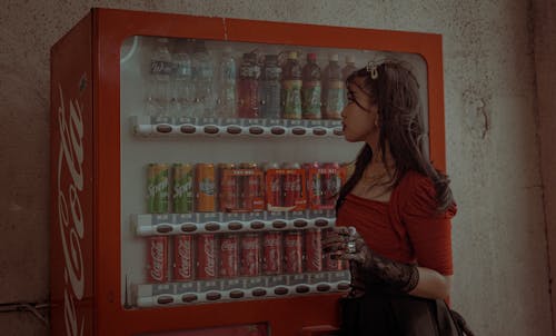 Woman in Red Top Standing Beside the Vending Machine