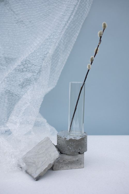 Free A modern minimalist composition featuring a twig in a glass vase with concrete elements. Stock Photo