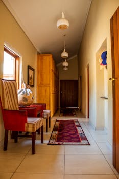 Elegant corridor with armchairs, warm lighting, and decorative rugs in a modern apartment.