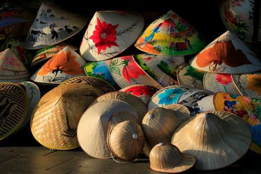 A vibrant collection of traditional Asian conical hats with floral patterns displayed at a market stall.