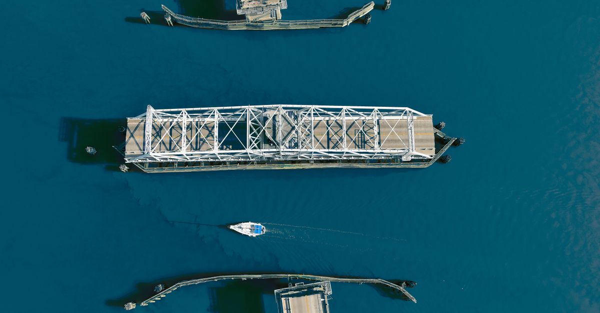 Aerial shot of a swing bridge opening over a strait with a sailing boat below, located in Beaufort, SC.