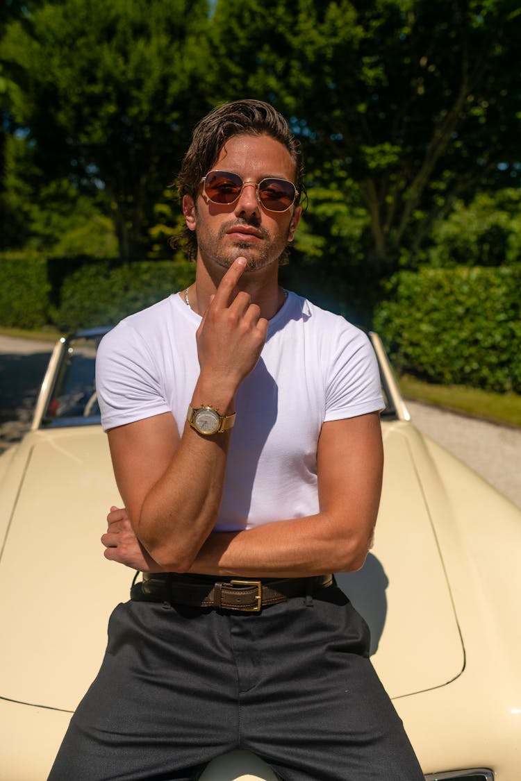 Man In White Shirt Sitting On Car Hood