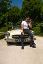 Man in White T-shirt and Black Pants Sitting on White Mercedes Benz Car