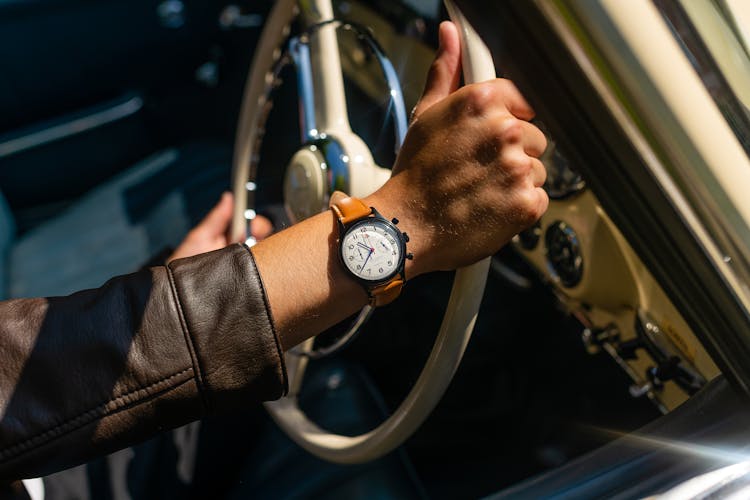 Person Wearing Brown Wristwatch While Holding A Steering Wheel