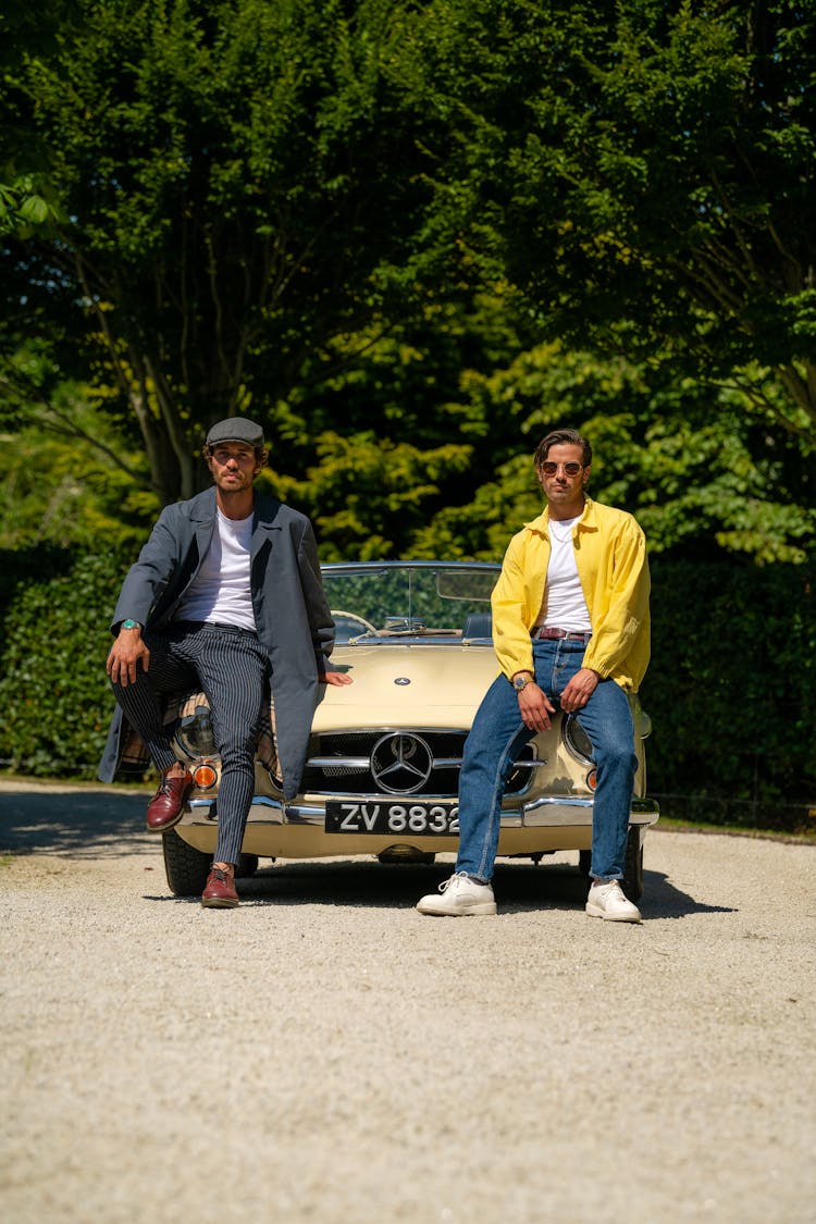 Two Men Sitting On Car Hood