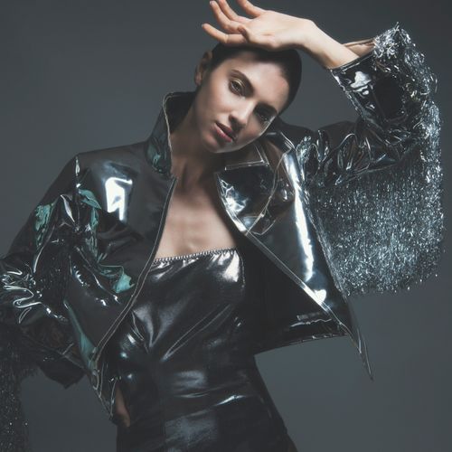 Free Elegant portrait of a model in a glossy metallic outfit with dramatic pose in a studio setting. Stock Photo