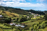 葡萄牙阿索雷斯山脉的田野郁郁葱葱，农舍点缀其间，天空充满活力