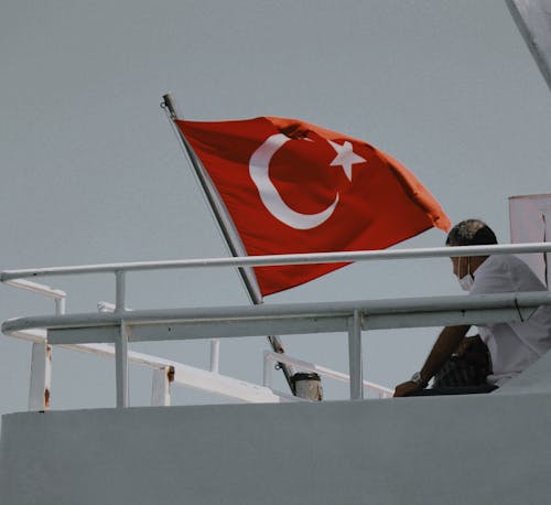 Free Man Sitting Near the Flag of Turkey Stock Photo