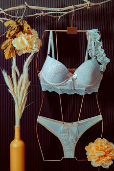 Lace lingerie set creatively displayed on hanger with decorative floral elements.