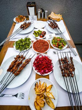 A vibrant spread of grilled skewers, salads, and dips on a wooden table, ideal for food enthusiasts.