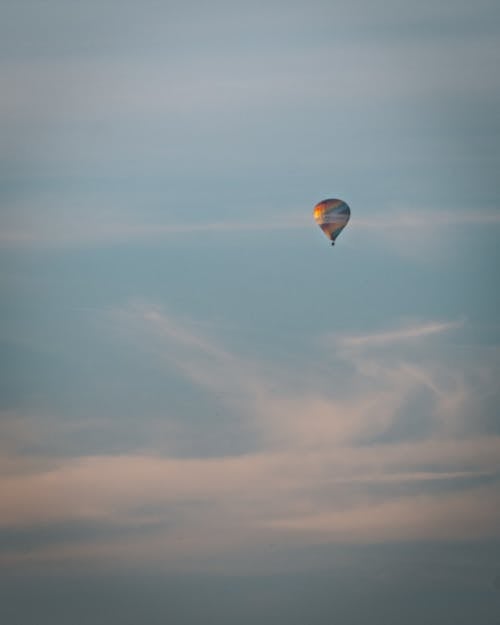 Orange and Yellow Hot Air Balloon in Mid Air Under Blue Sky