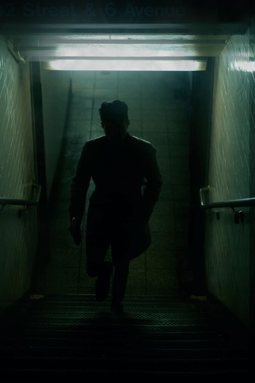 Free A silhouette of a man walking up dimly lit subway stairs, creating a mysterious urban scene. Stock Photo