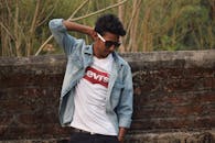 年轻人穿着牛仔夹克，戴着墨镜，显得时尚又自信