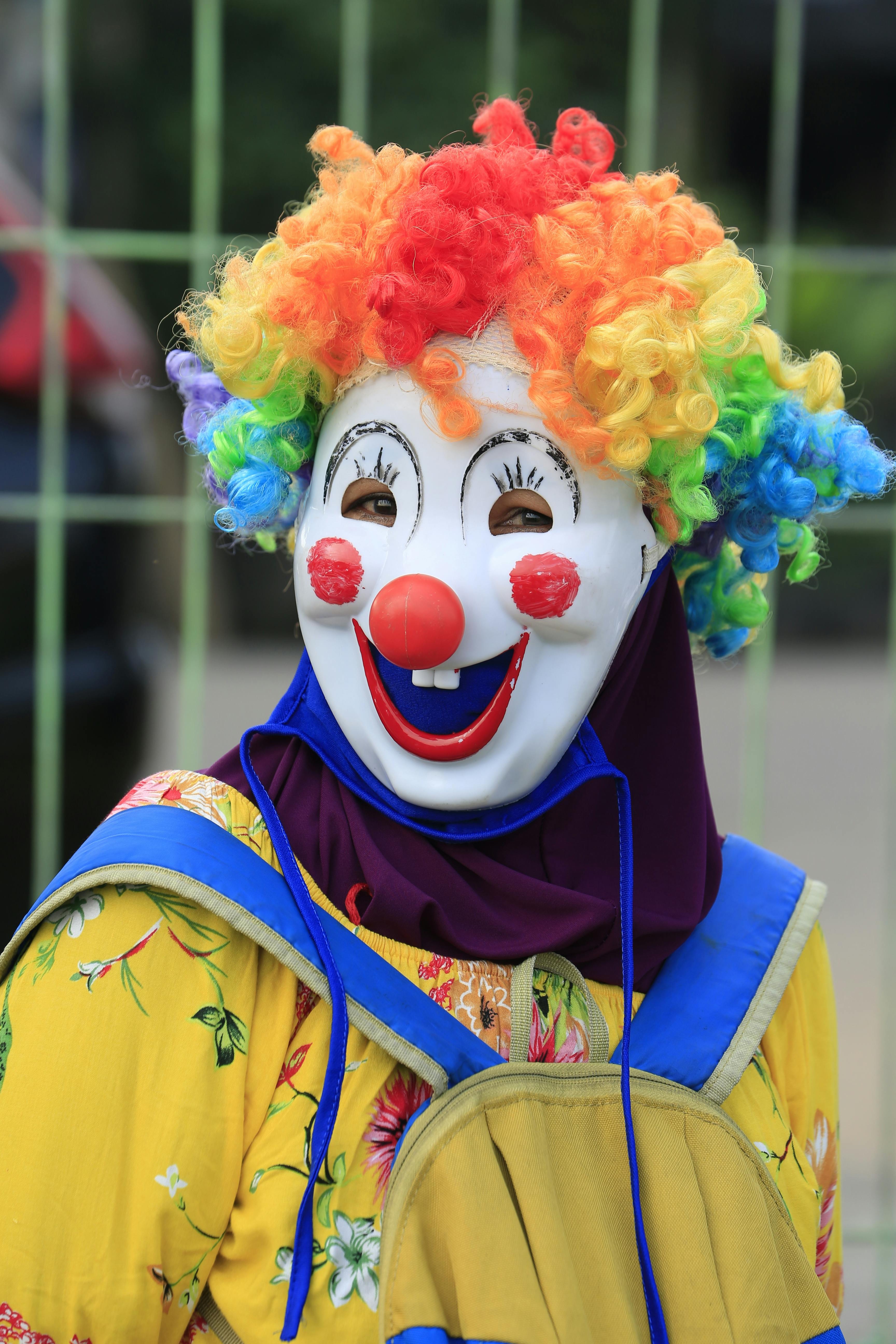 Free A vibrant clown in a rainbow wig and mask smiling brightly outdoors. Stock Photo