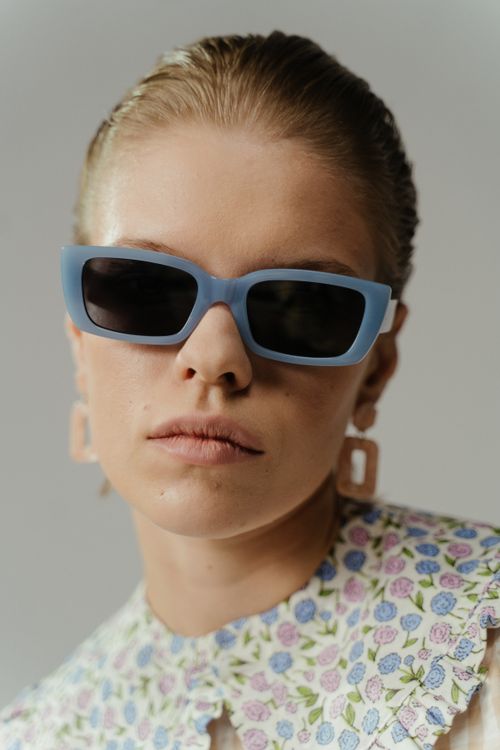 Free Close-up portrait of a woman wearing retro-fashion sunglasses and statement earrings. Stock Photo