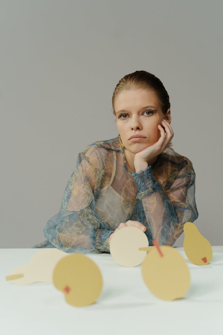 Sad Woman Sitting In Front Of Paper Cutouts