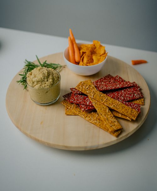 Free A wooden tray with hummus, assorted crackers, and fresh vegetables for a healthy snack. Stock Photo