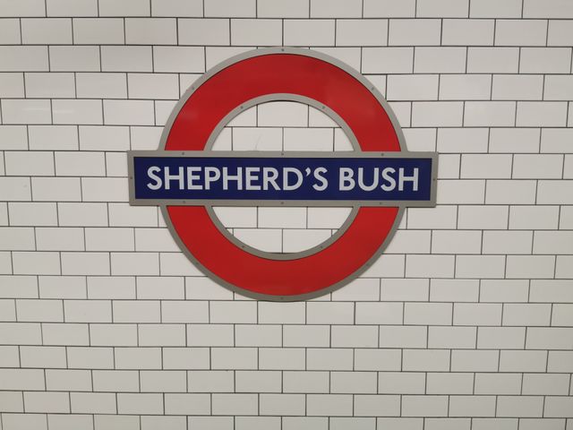 The Shepherd’s Bush Underground station sign on a tiled wall.