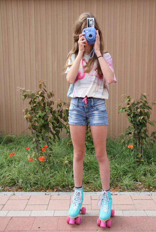 Woman in Blue Denim Shorts Wearing Blue and Pink Roller Skates