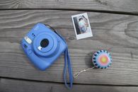 A Close-Up Shot of an Instant Camera and a Yoyo on a Wooden Surface