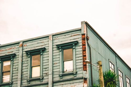 Free Corner view of a vintage blue wooden building showing weathered details and windows. Stock Photo