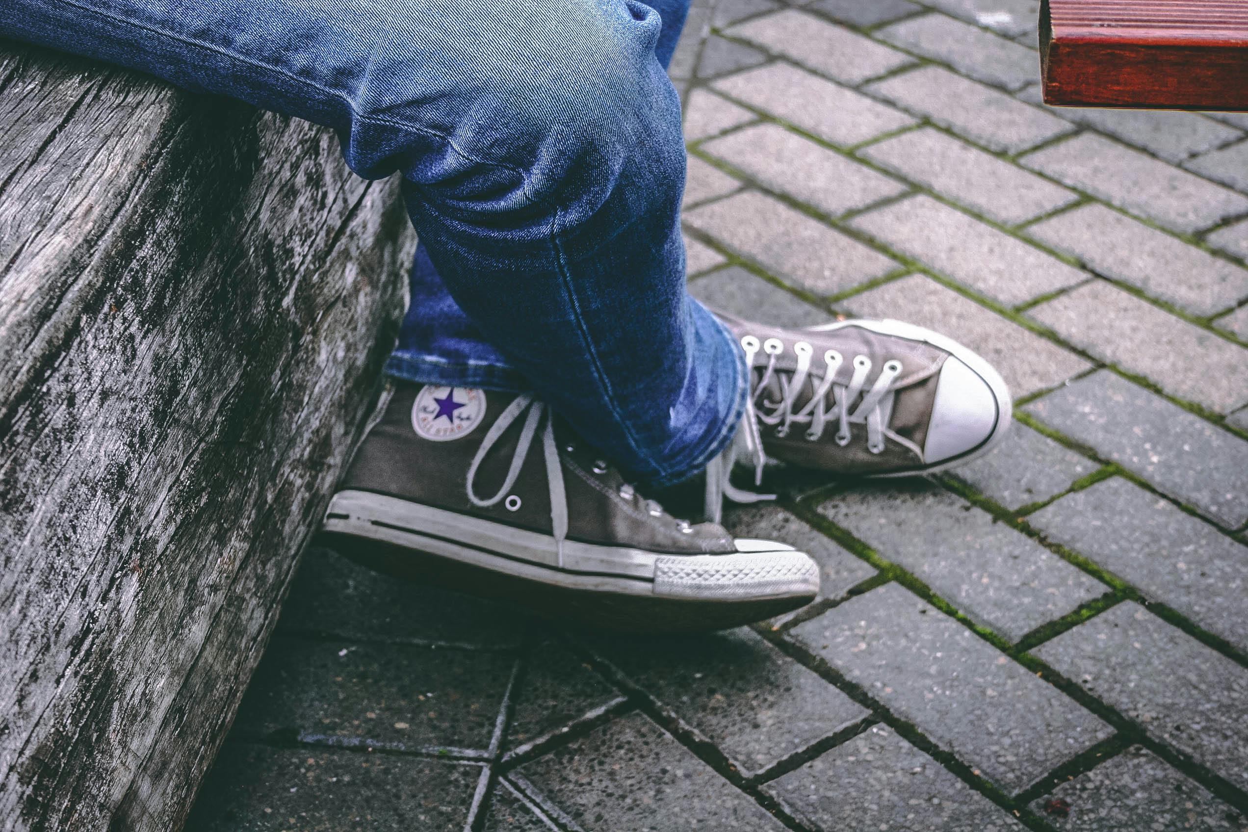 Person Wearing Brown Converse All-star High-top Sneakers and Blue Denim  Jeans While Sitting on Bench · Free Stock Photo