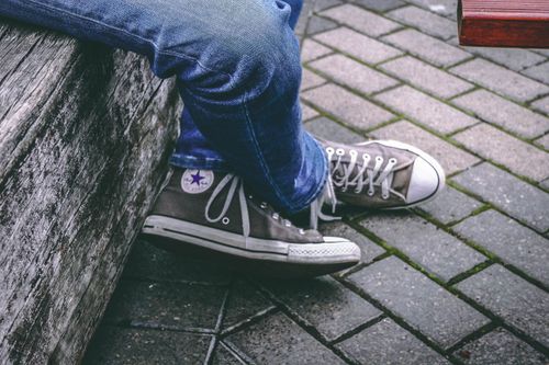 Free Close-up of casual sneakers and jeans on a cobblestone surface, relaxed outdoor style. Stock Photo