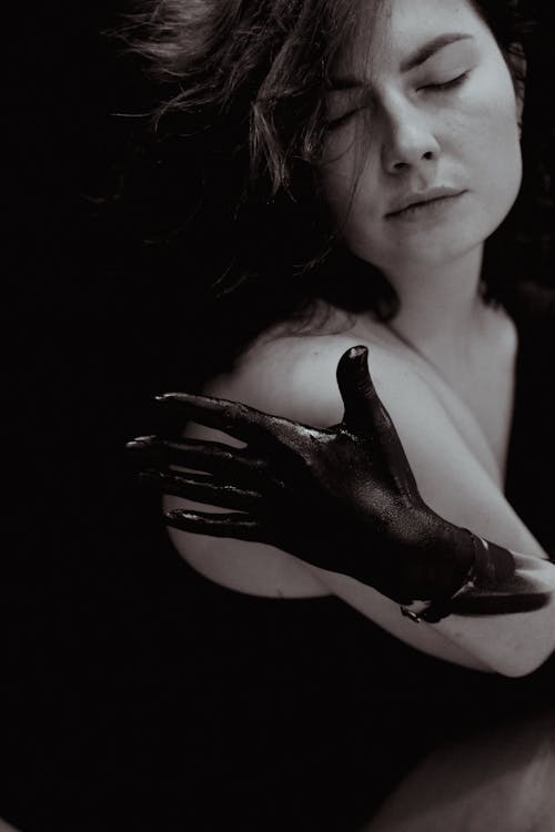 Portrait of a Young Woman With a Hand Covered in Black Paint